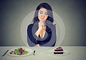 Dieting concept, woman choosing between healthy food and tasty cake