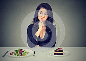 Dieting concept, woman choosing between healthy food and tasty cake photo