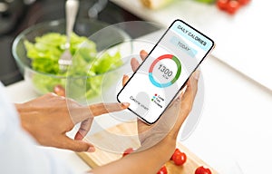 Dieting Concept. Woman eating salad and counting calories with app on smartphone