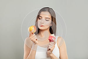 Dieting concept. Young Woman choosing between Fruits and Sweets