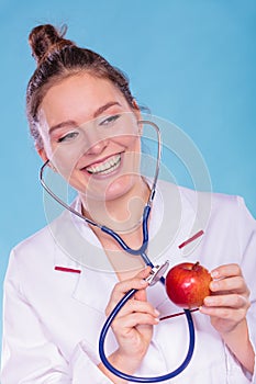 Dietitian examine apple fruit with stethoscope.