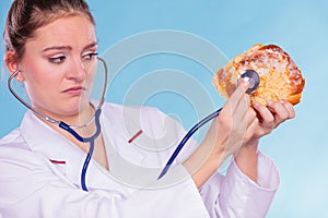 Dietitian examine sweet roll bun with stethoscope.