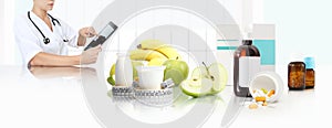 Dietitian nutritionist doctor prescribes prescription by consulting the digital tablet at the desk office with fruits and yogurt photo