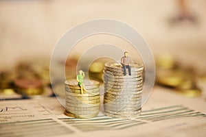 Differences between womenâ€™s and menâ€™s income or salary concept with miniature silhouettes on stack of coins