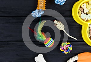 Different accessories for dogs and cats: mouse toy, ball, comb, leash, collar, toys on black wooden background. Pets care