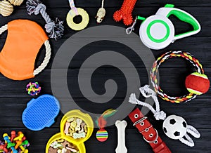 Different accessories for dogs and cats: mouse toy, ball, comb, leash, collar, toys on black wooden background. Pets care