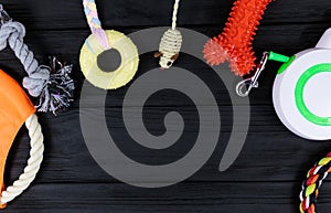 Different accessories for dogs and cats: mouse toy, ball, comb, leash, collar, toys on black wooden background. Pets care