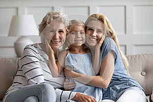 Different age and generation relatives beautiful women hugging posing indoors