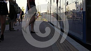 Different age people expect transport at the bus stop. Take off close of people`s feet go into the tram