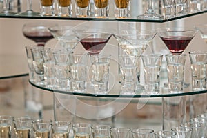 Different alcohol drinks on a glass stand. wine, champagne, cognac, vodka, martini