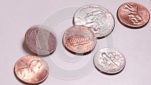 Different American coins rotate and stop in the frame. Close-up. US Small Metal Cash. Movement on a white table. The