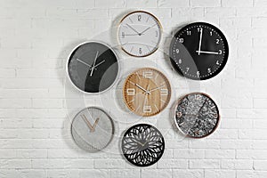 Different analog clocks hanging on white wall.