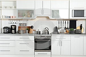 Different appliances, clean dishes and utensils on kitchen