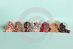 Different assortment of peppers and spices in transparent tubes on the turquoise background