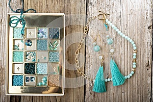 Different azure beads and chrystals in box handmade jewelry  around old style wooden background. close up