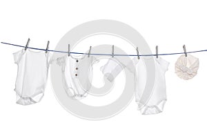 Different baby clothes drying on laundry line against white background