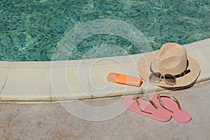 Different beach accessories near outdoor swimming pool on sunny day, space for text