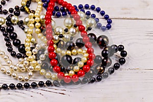 Different beads necklaces on white wooden background