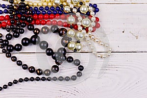 Different beads necklaces on white wooden background