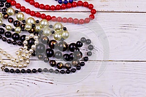 Different beads necklaces on white wooden background
