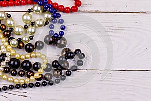 Different beads necklaces on white wooden background