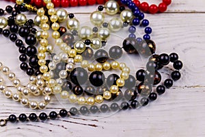 Different beads necklaces on white wooden background