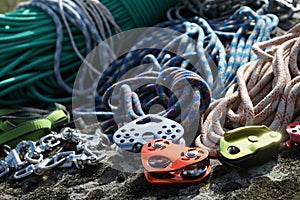 Different belay devices and ropes on rock, closeup. Climbing equipment