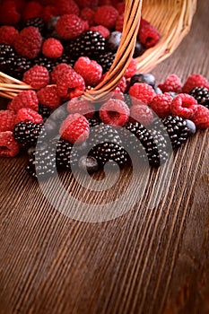 Different berries in a basket on a wooden table