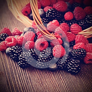 Different berries in a basket on a wooden table