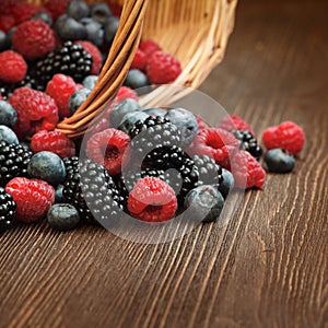 Different berries in a basket on a wooden table