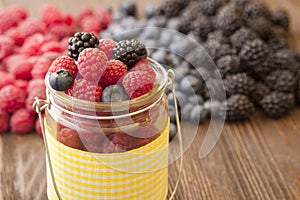 Different berries in a basket on a wooden table