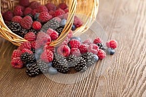 Different berries in a basket on a wooden table