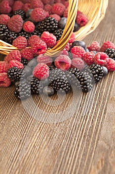 Different berries in a basket on a wooden table