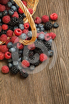 Different berries in a basket on a wooden table