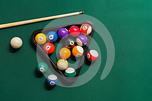 Different billiard balls with cue and rack on green table