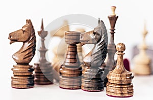 Different black and white wooden chess pieces, horse in the foreground, leadership background