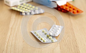 Different blisters with tablets on a wooden table