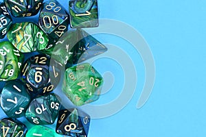 Different blue and green roleplaying RPG dice on side of blue background
