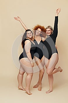 Different Body Types. Group Of Diversity Models Full-length Portrait. Blonde, Brunette And Redhead In Black Bodysuits Posing.