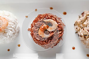 Different boiled rice with shrimps on plate, closeup