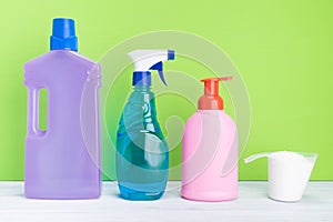 Different bottles with detergents for cleaning on a green background