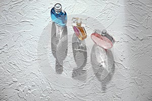 Different bottles of perfume on white textured background