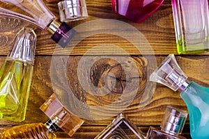 Different bottles of perfume on a wooden background. Top view, copy space