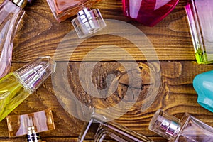 Different bottles of perfume on a wooden background. Top view, copy space