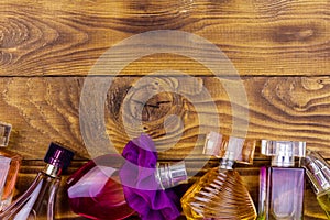 Different bottles of perfume on a wooden background. Top view, copy space