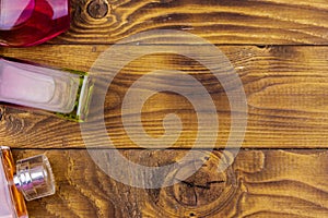 Different bottles of perfume on a wooden background. Top view, copy space