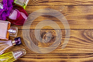 Different bottles of perfume on wooden background. Top view, copy space