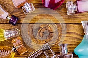 Different bottles of perfume on wooden background. Top view, copy space