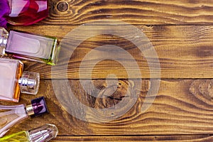 Different bottles of perfume on wooden background. Top view, copy space