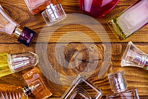 Different bottles of perfume on wooden background. Top view, copy space